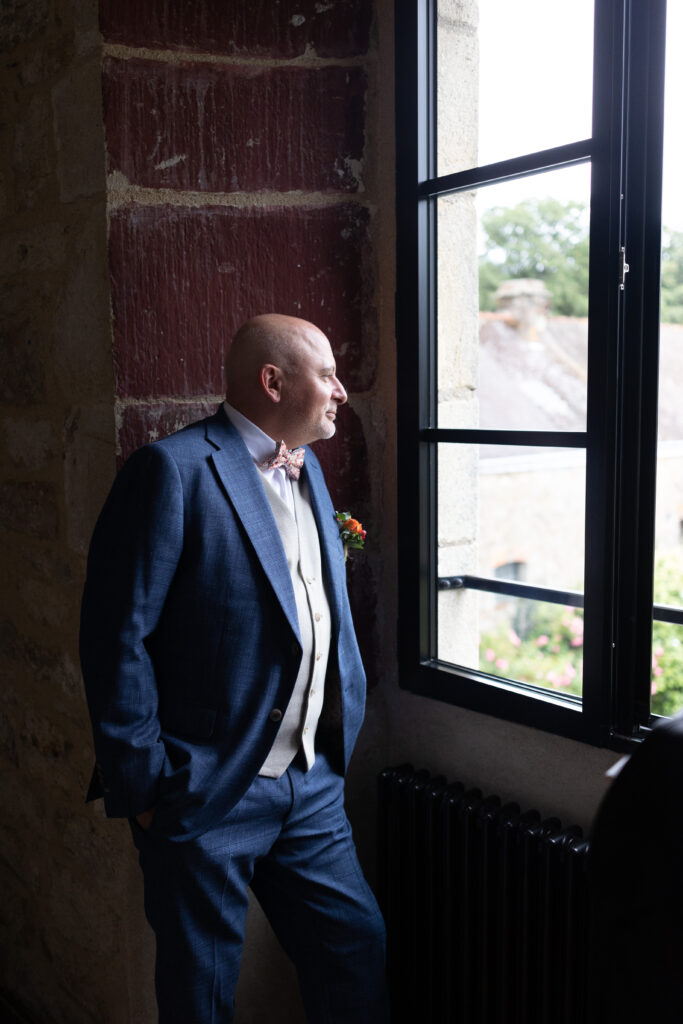 Marié qui regarde par la fenêtre en pleine organisation de mariage à Rennes